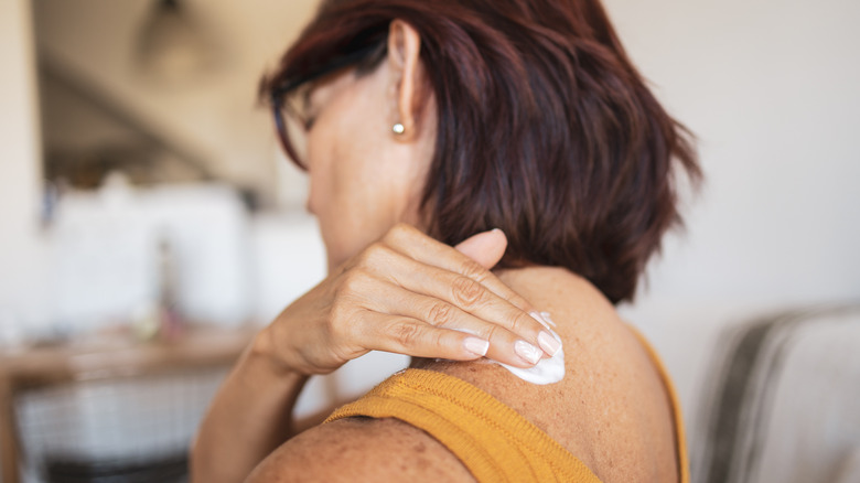 woman applying lotion on back