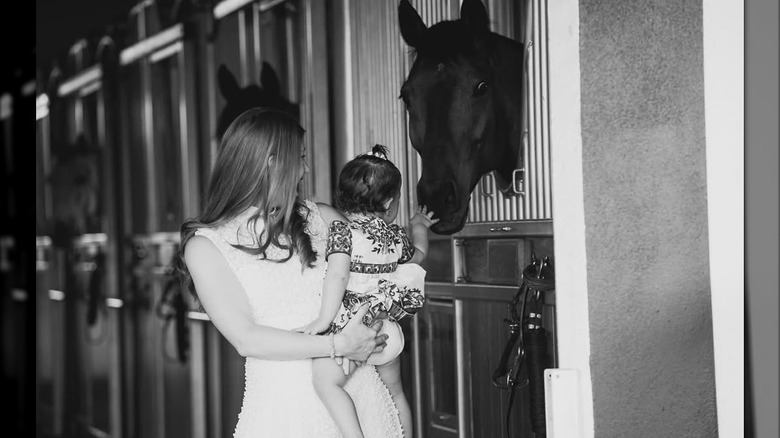 Jennifer Gates holds her daughter Leila as the toddler touches a horse in this photo posted in May 2024 (2024)