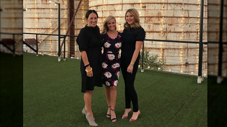 Joanna Gaines wearing black smiling next to Reese Witherspoon in a floral dress and Jenna Bush Hager in all black.