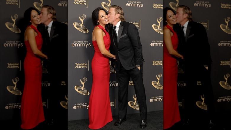 Chip Gaines wearing a suit and kissing wife Joanna Gaines wearing a red dress at a red carpet event.