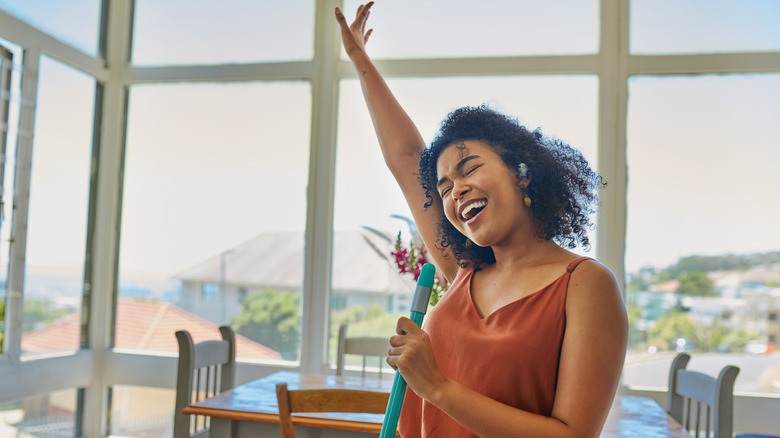 Woman sings into mop handle