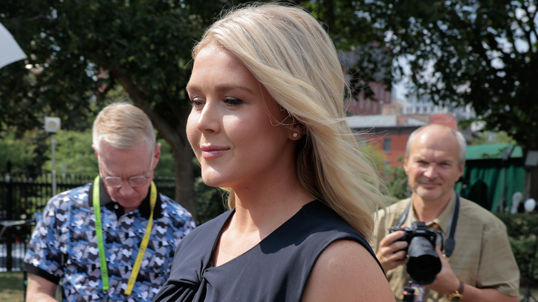 Karoline Leavitt walking outside the White House in a black dress