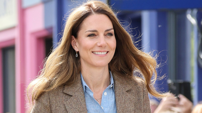 Kate Middleton smiles with honey blonde hair while walking down a street in Scotland
