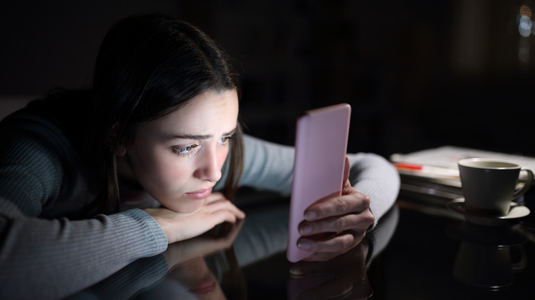 Woman looks sadly at phone