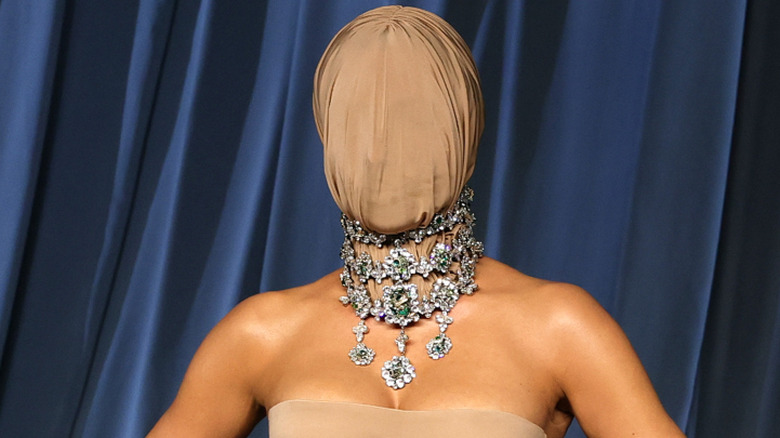 Kim Kardashian wearing a tan dress and face covering at the 2025 Academy Museum Gala