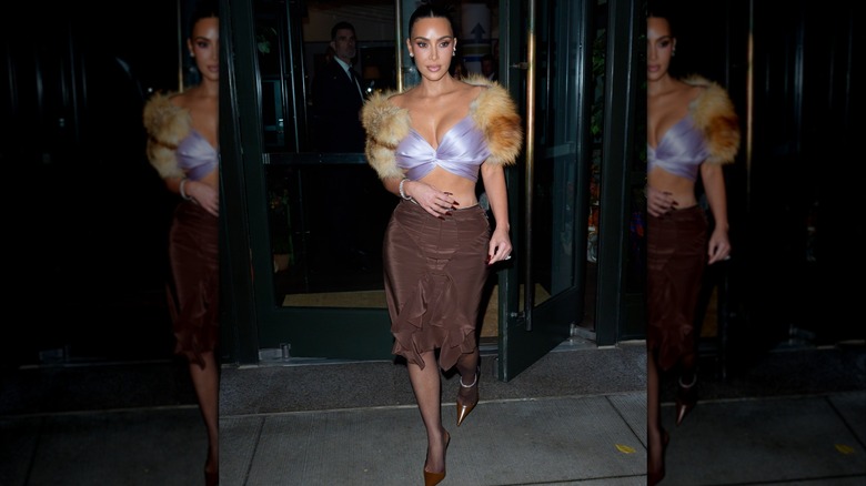 Kim Kardashian is photographed wearing a lilac fur-trimmed top and brown skirt in New York City in 2025.