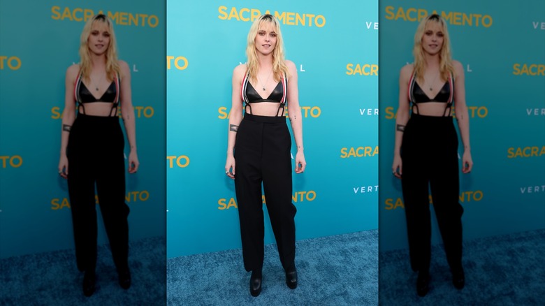 Kristen Stewart posing in pants, suspenders, and a leather bra