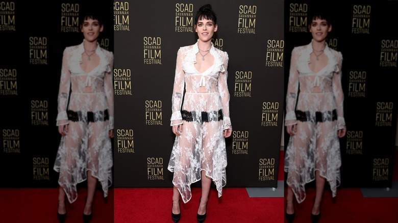 Kristen Stewart posing in a sheer lace white dress