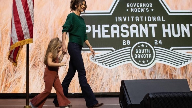 Kristi Noem holds her granddaughter's hand on stage