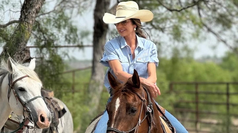 Kristi Noem riding while wearing a cowboy hat