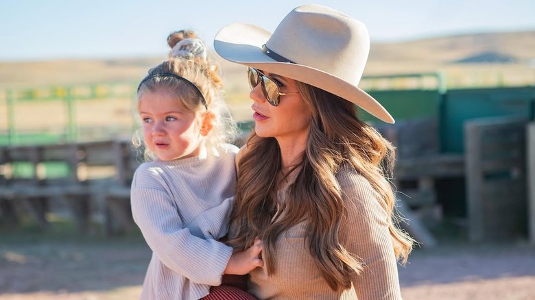 Kristi Noem holding a child while wearing cowboy hat