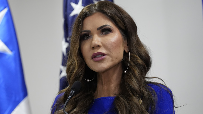 Kristi Noem in a blue dress speaking after communicating with Chile's Minister of Public Security