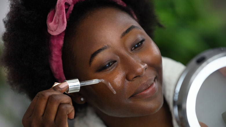 young woman applying face serum