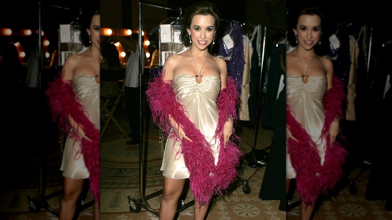 Lacey Chabert poses for a photo in a cocktail dress and boa