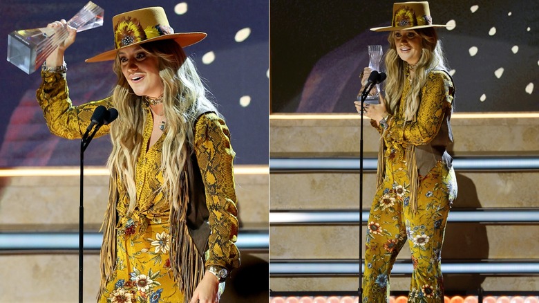 Lainey Wilson wearing a yellow outfit with a cowboy hat and fringed vest