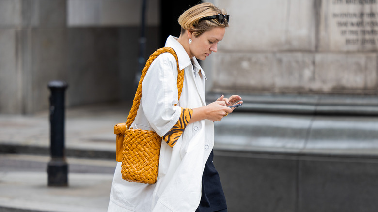 woman holding leather woven bucket bag