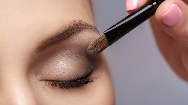Hand applying eyeshadow to model's eyelid