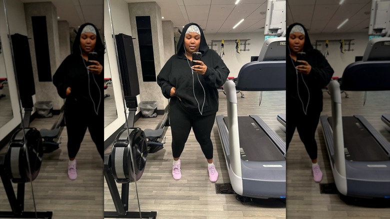 Lizzo posing in a selfie in a gym wearing a hoodie