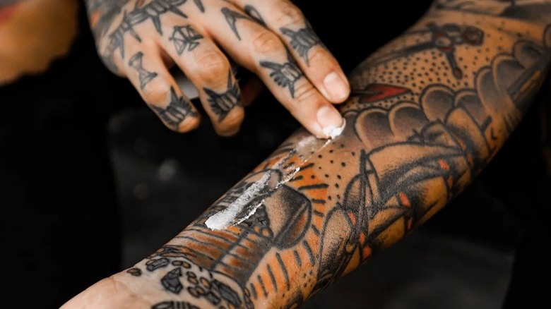 Person applying tattoo balm on forearm