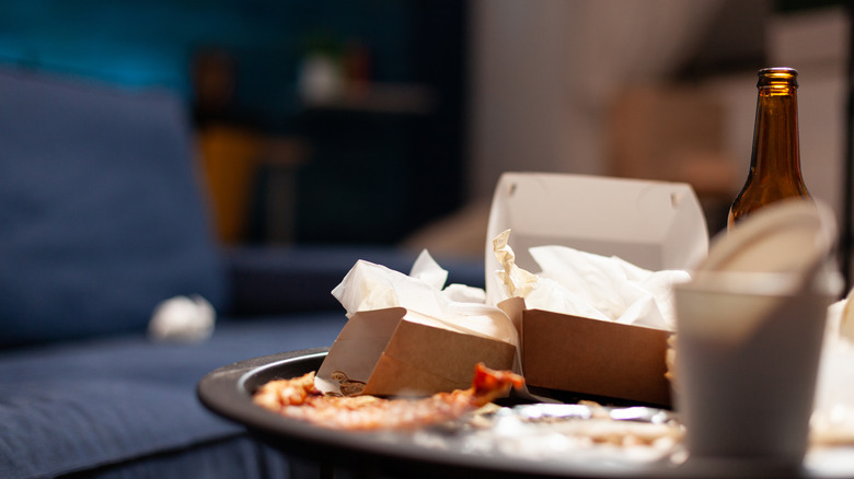 trash pile in living room of boxes and beer bottle