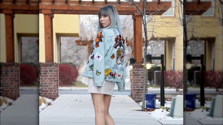 Woman wearing denim jacket with embroidered patches
