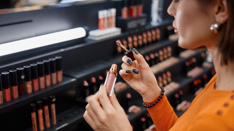 A woman shopping for lip gloss in a beauty supply store