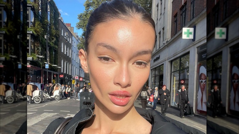 A woman wearing pink lipstick on a bronzed face