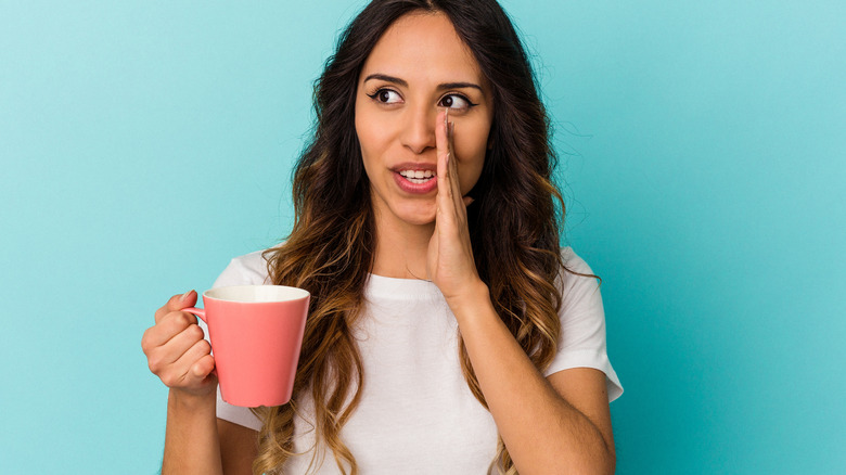woman holding cup whispering what she wants