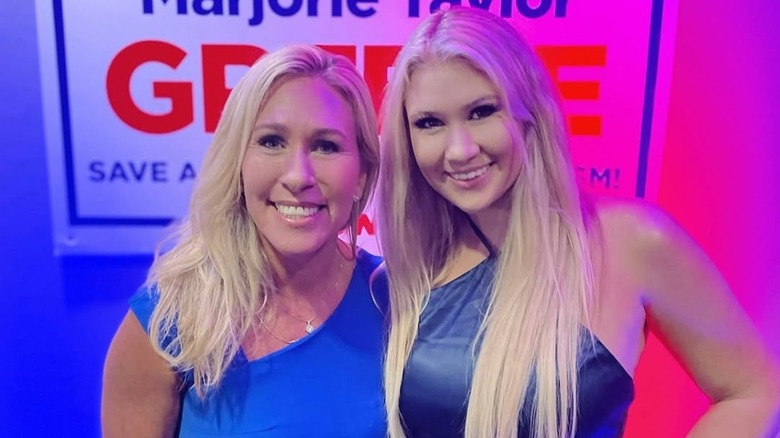 Marjorie Taylor Greene and her daughter, Lauren Greene Sanders, smile while standing side by side at a political rally