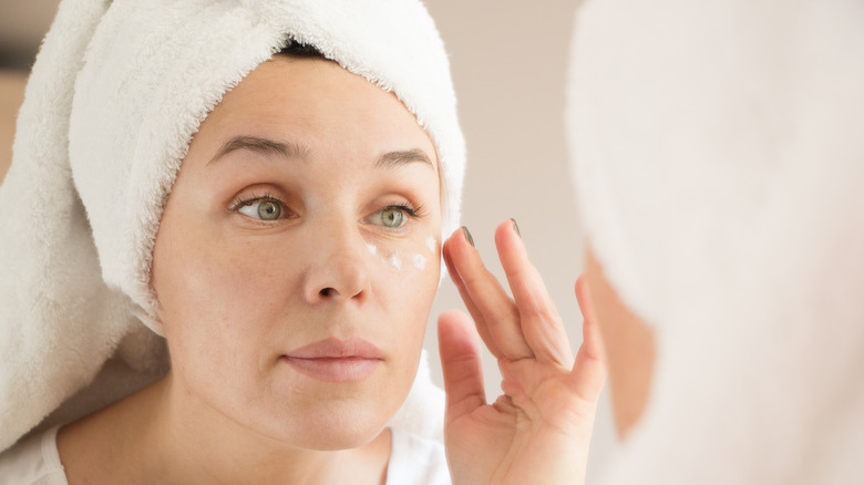 Woman applying moisturizer under eyes