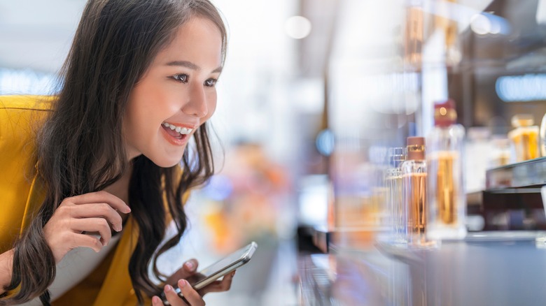Woman looking at perfume and smiling