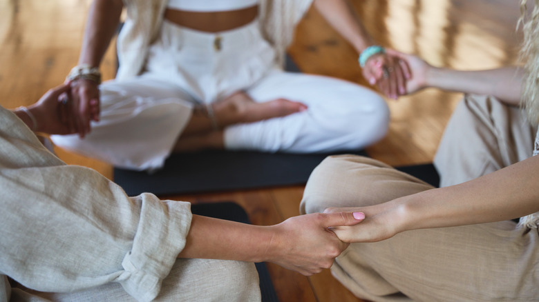 A group of mindful women sitting in a circle and holding hands
