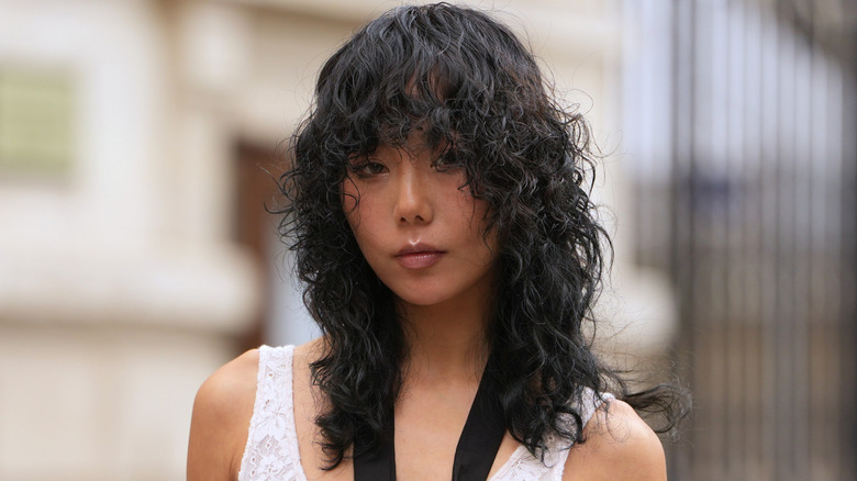 A woman with a curly black shag cut