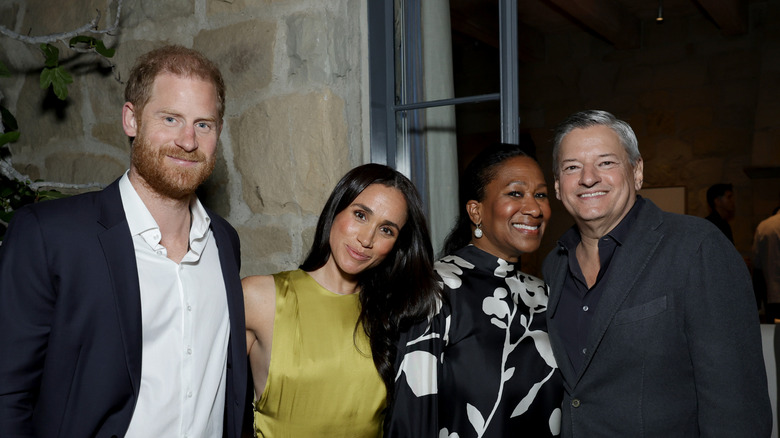 Prince Harry, Meghan Markle, Nicole Avant, and Ted Sarandos pose for a photo together at an outdoor party