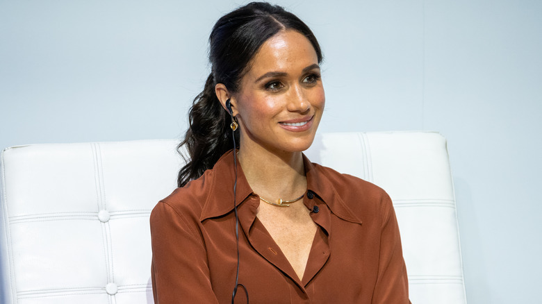 Meghan Markle listening attentively with a low fluffed ponytail.