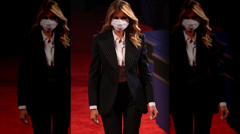Melania Trump wearing a black and white pinstripe suit while walking across a red carpet