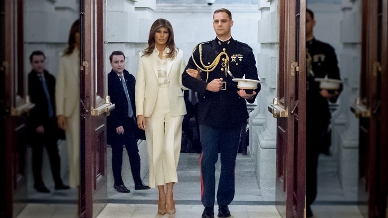 Melania Trump wearing a pantsuit walking arm-in-arm with a U.S. Marine Corps officer