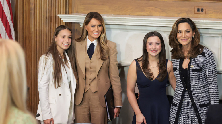 Melania Trump wearing a Ralph Lauren pantsuit smiles as she takes a picture with other ladies