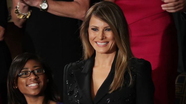 Melania Trump smiling in a black look in Congress