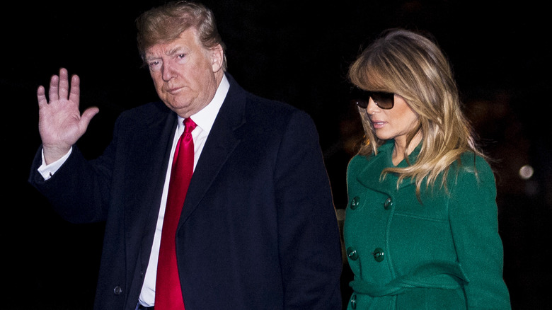 Melania Trump wears a green coat while walking with Donald Trump