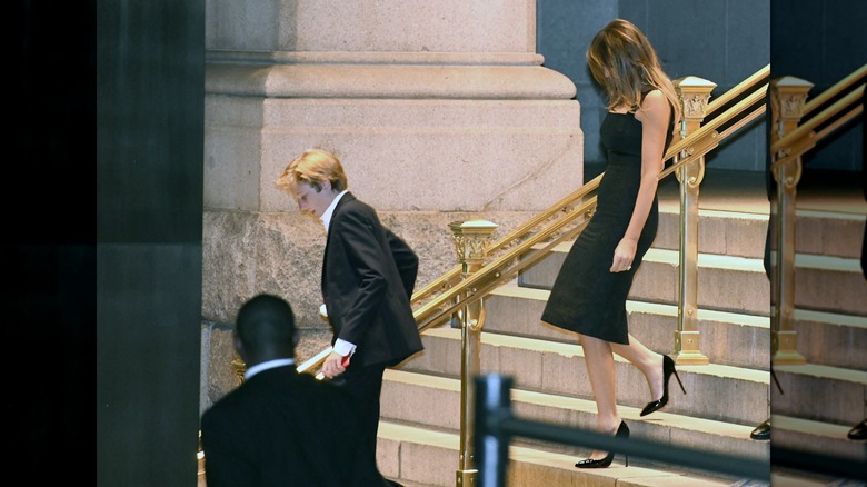 Melania Trump walking in a tight black midi dress