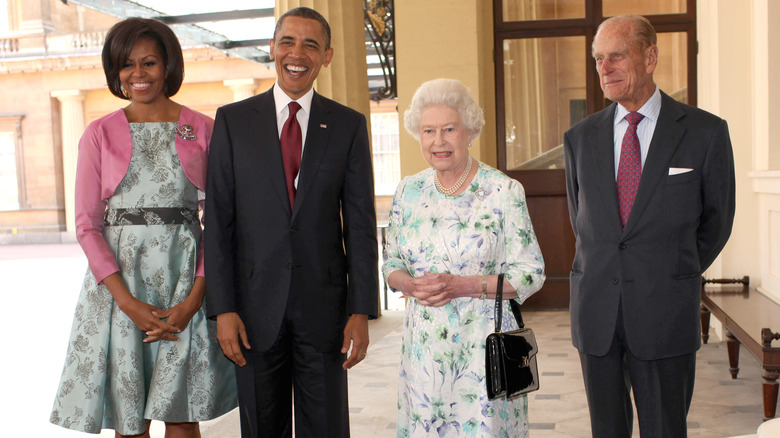 Michelle Obama posing with Barack Obama, Queen Elizabeth, and Prince Phillip