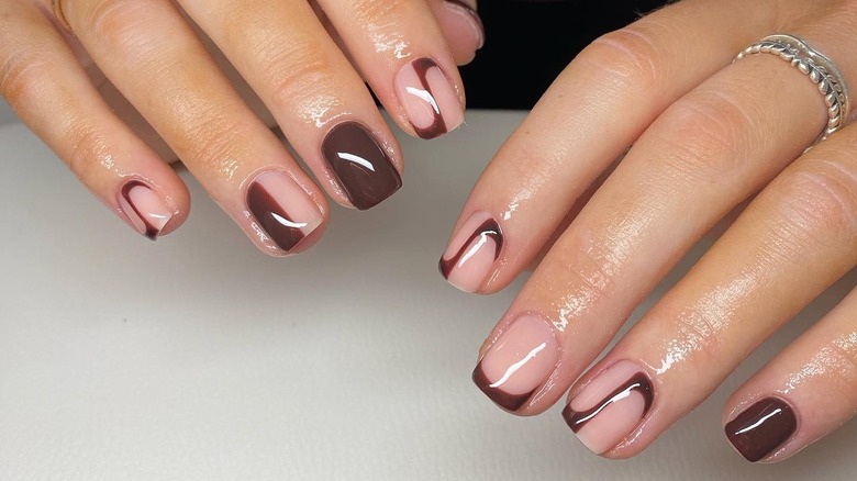 Hands featuring short nails, brown polish