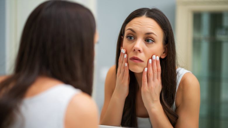 A woman examining her face