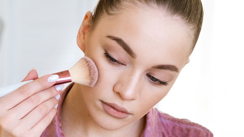 woman applying blush on face
