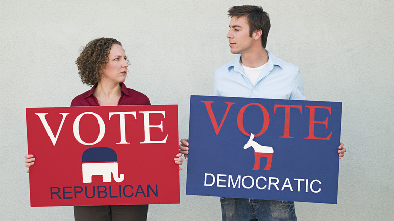 two voters holding different party signs