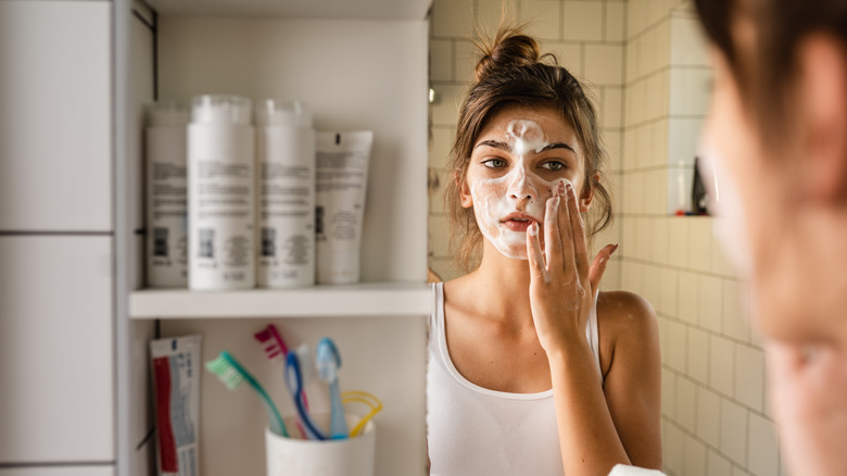 woman applying face mask in mirror