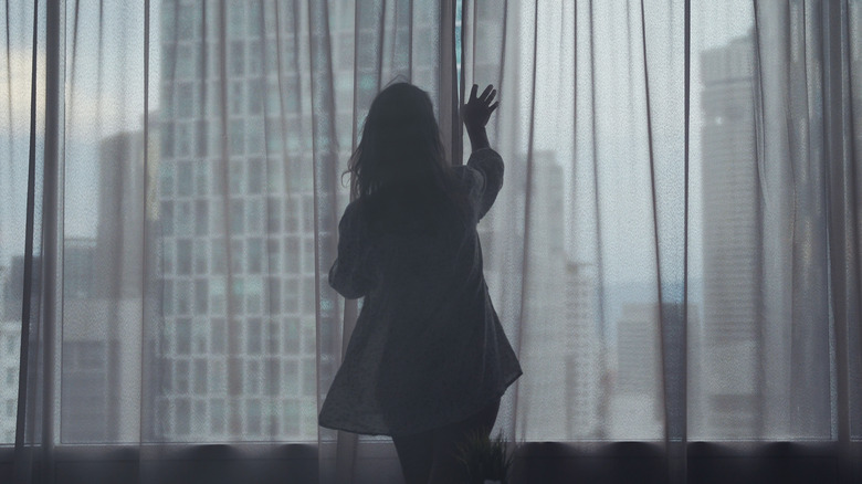 woman opening window curtains