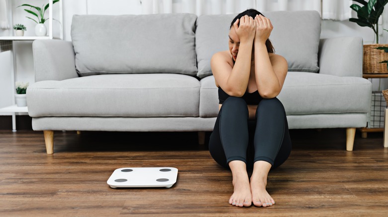 stressed woman sitting next to scales