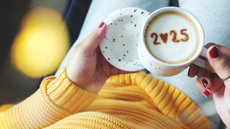 Woman with red nails holding a coffee with 2025